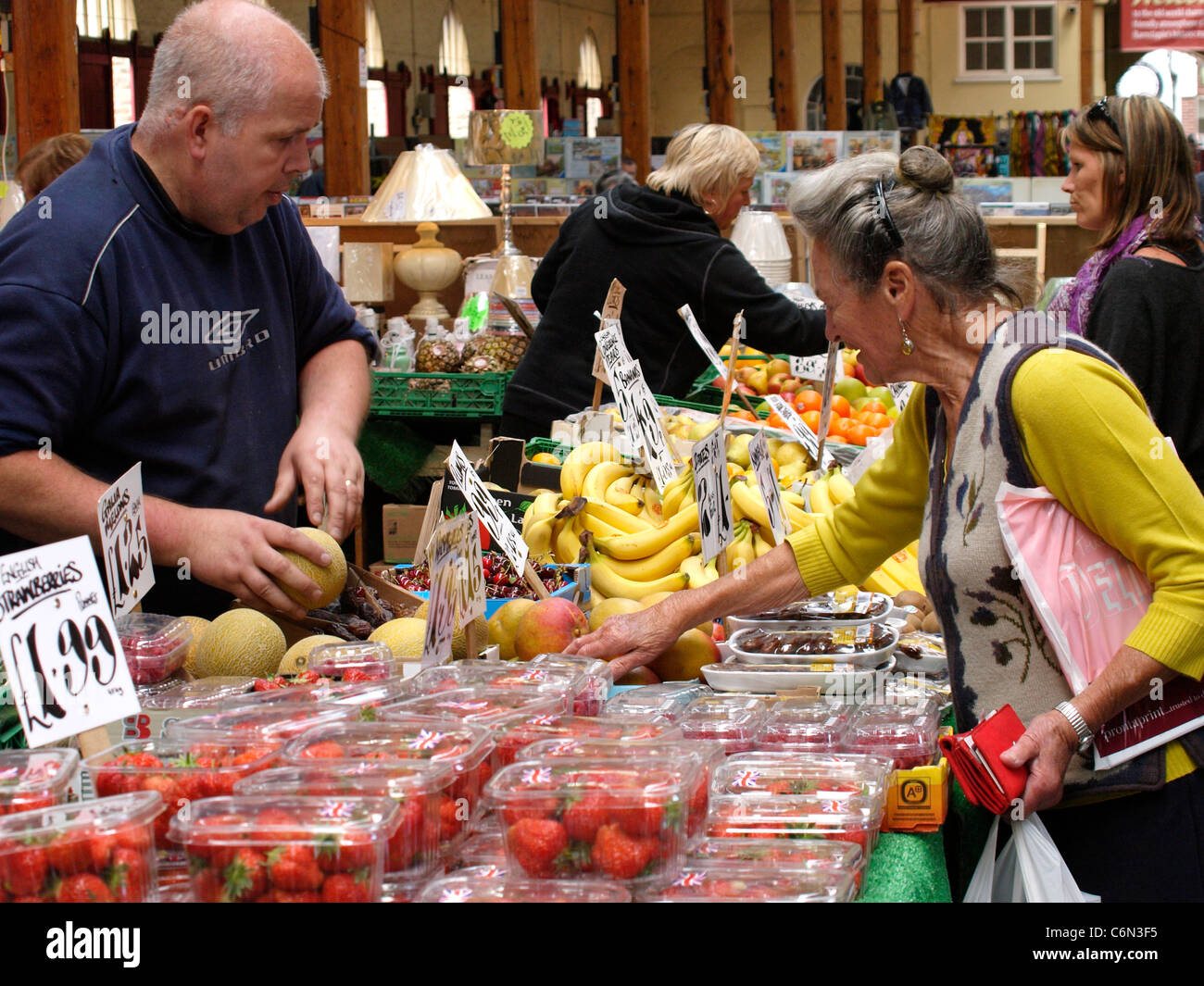 Rentner kaufen Obst und Gemüse aus einem Markt Händler, Barnstaple Pannier Markt, Devon, UK Stockfoto