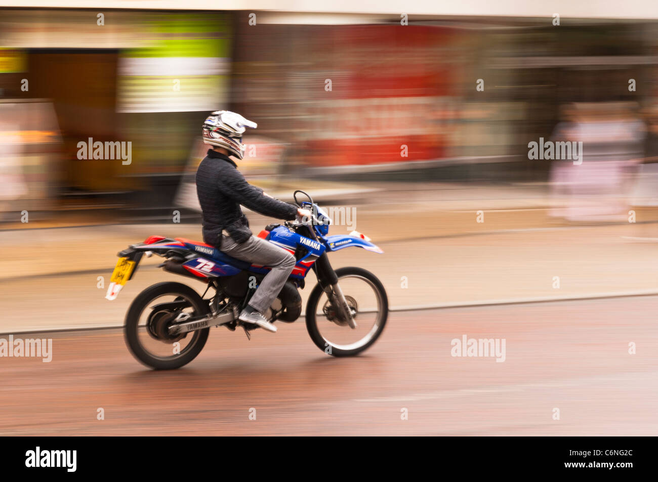 Ein Mann auf einem Motorrad Fahrten durch die Stadt und zeigt absichtlich Bewegungsunschärfe in Norwich, Norfolk, England, Großbritannien, Uk Stockfoto