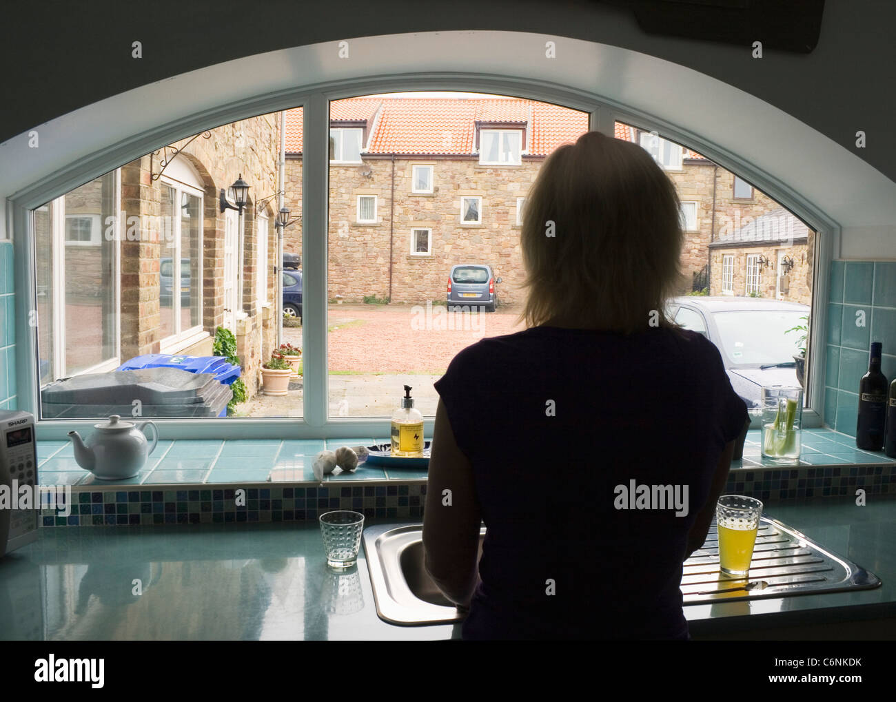 Silhouette der Frau stand am Küchenfenster. Stockfoto