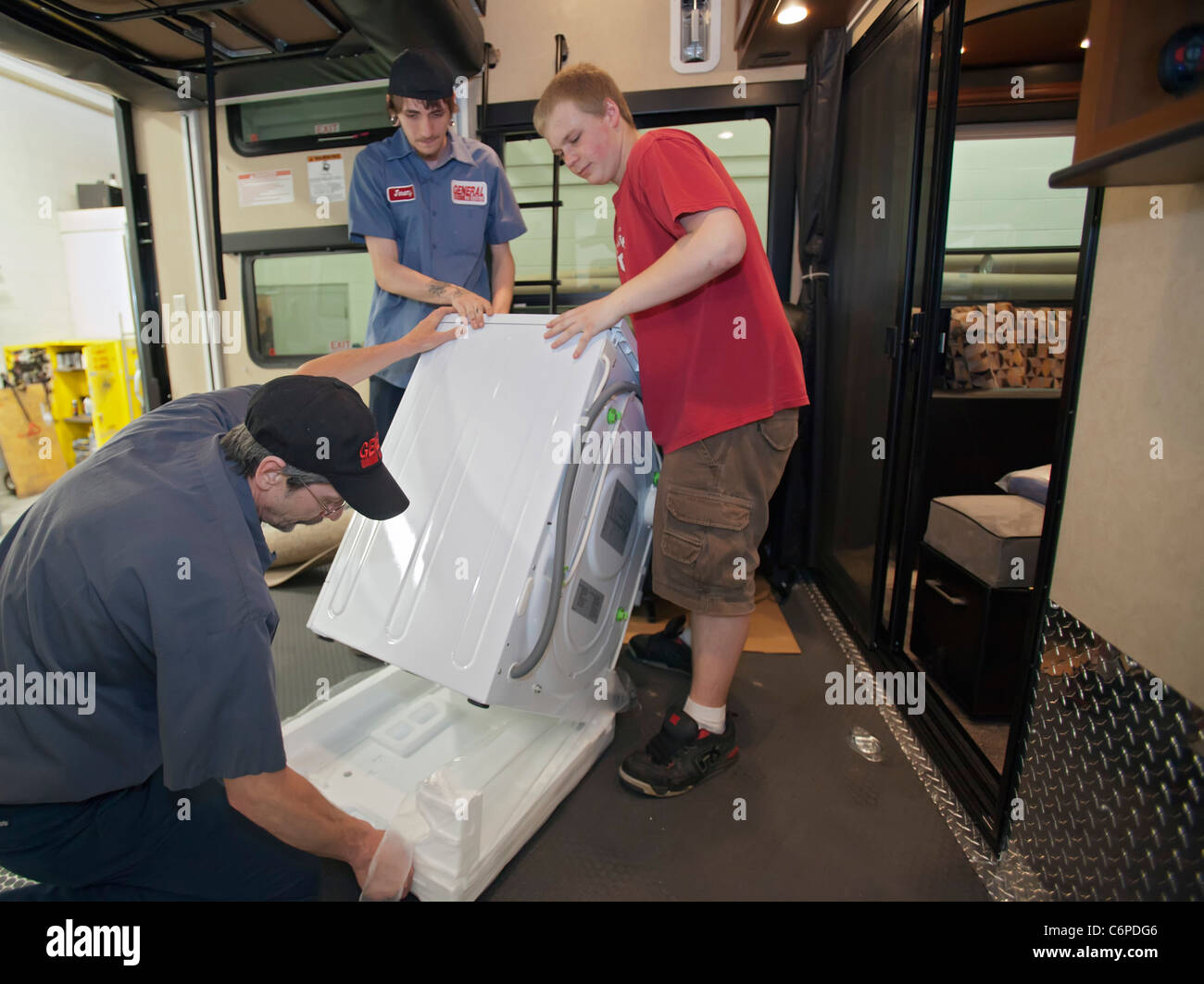 Wixom, Michigan - Arbeiter installieren eine Waschmaschine in einem Luxus-RV bei einem Freizeitfahrzeug-Händler. Stockfoto