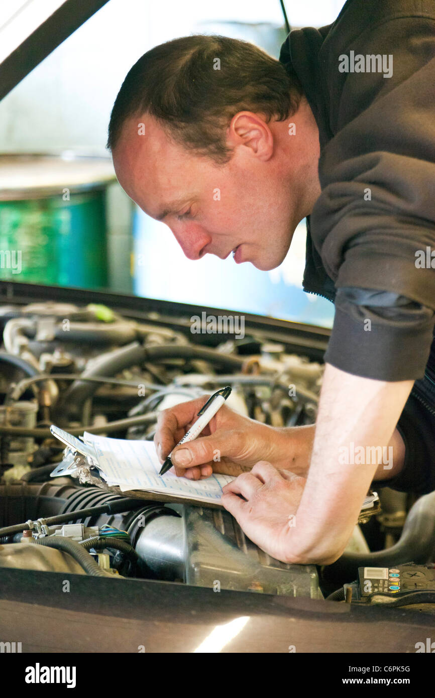 Garage Mechaniker überprüfen die Unterseite eines Autos während einer TÜV-Prüfung im Vereinigten Königreich Stockfoto