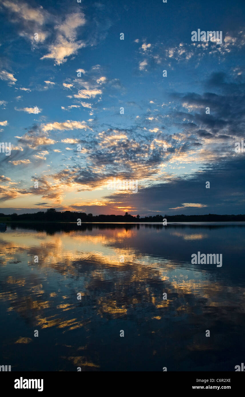 Der Sonnenuntergang spiegelt sich in einem ruhigen See im Norden Minnesotas, USA, wider Stockfoto