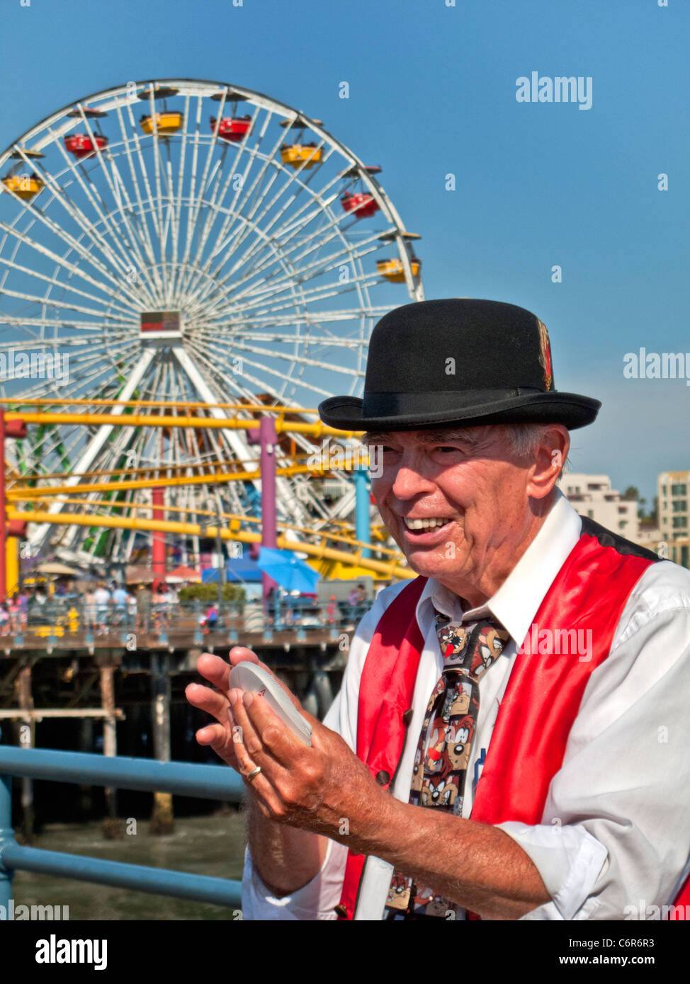 Ein älterer Magier mischt Karten für sein Publikum im Vergnügungspark am Santa Monica Pier. Stockfoto