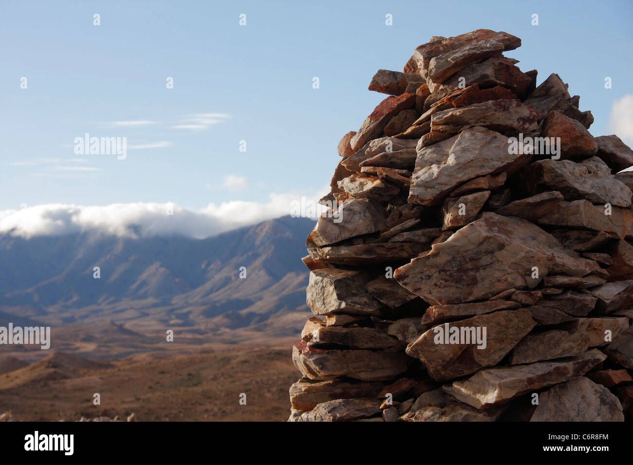 Halbwüstenartige Landschaft mit Wolken über den Rosuintjieberg-Bergen in der Ferne und Stein Haufen im Vordergrund. Stockfoto