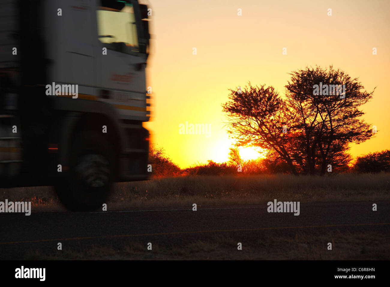 Trans-Kalahari-Sonnenuntergang mit einem vorbeifahrenden LKW Stockfoto