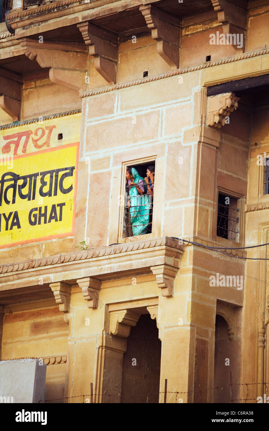 Zwei Frauen schauen aus dem Fenster eine Ghat die Fronten des Ganges in Varanasi, Indien im Staat Uttar Pradesh Stockfoto
