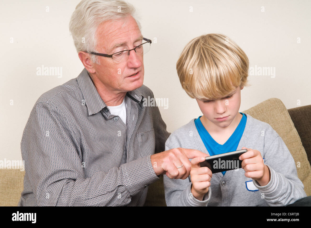 Das Kind lernt seinen Opa um ein Smartphone verwenden Stockfoto