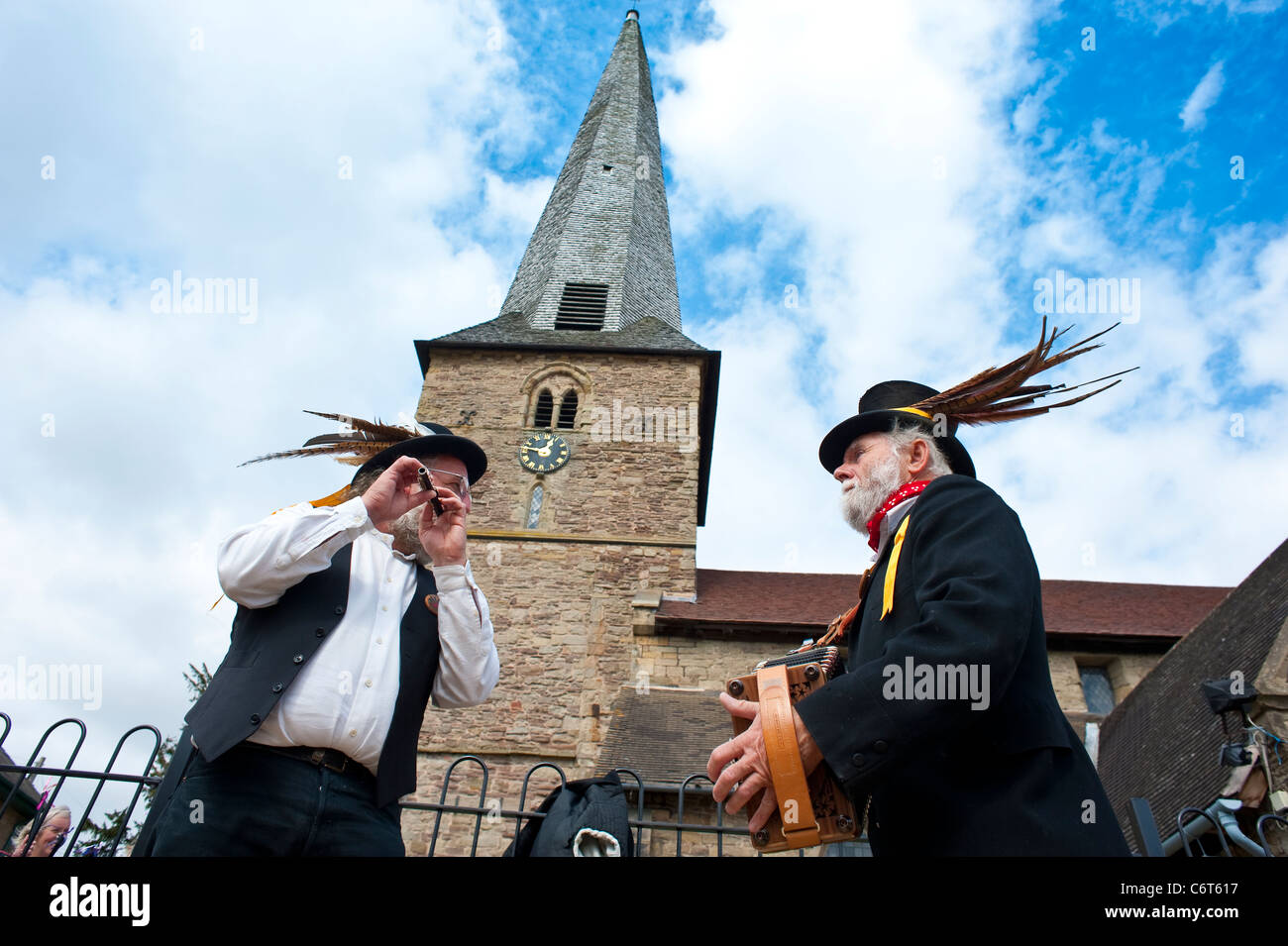 Morris Tanzmusiker spielen unter schiefen Turm der Pfarrkirche von Cleobury Mortimer Shropshire, England Stockfoto