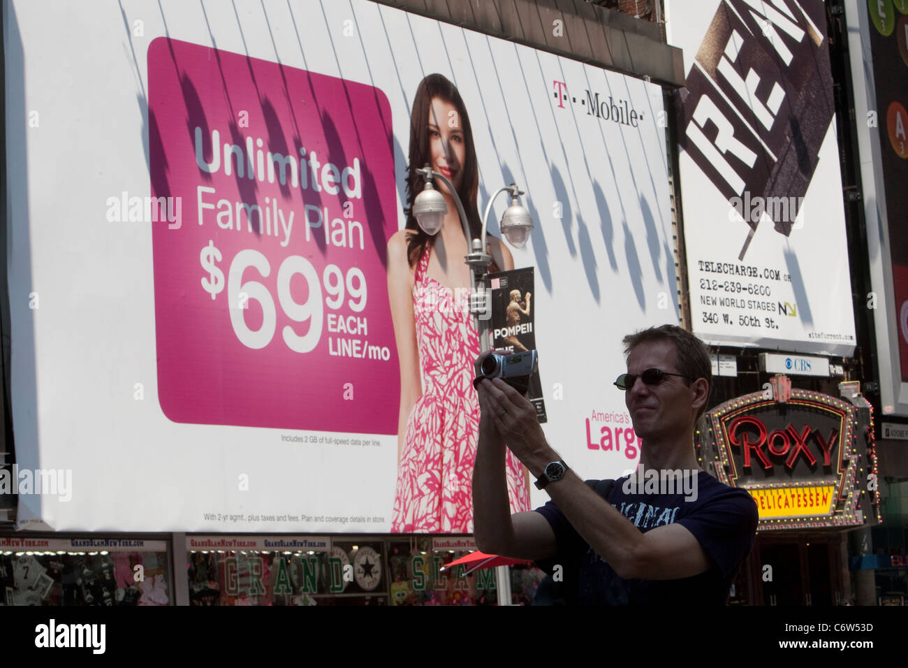 Ein Mann nimmt ein Foto vor einem T-Mobile Werbetafel am Times Square New Yorker Stadtteil Manhattan Stockfoto