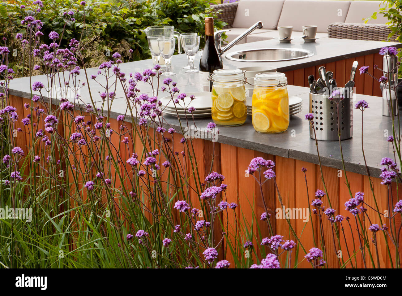 Moderner Garten im Freien Wohnterrasse Küchenbereich mit Arbeitsplatte und Außenmöbeln Grenze von Verbena bonariensis Sommer UK Stockfoto