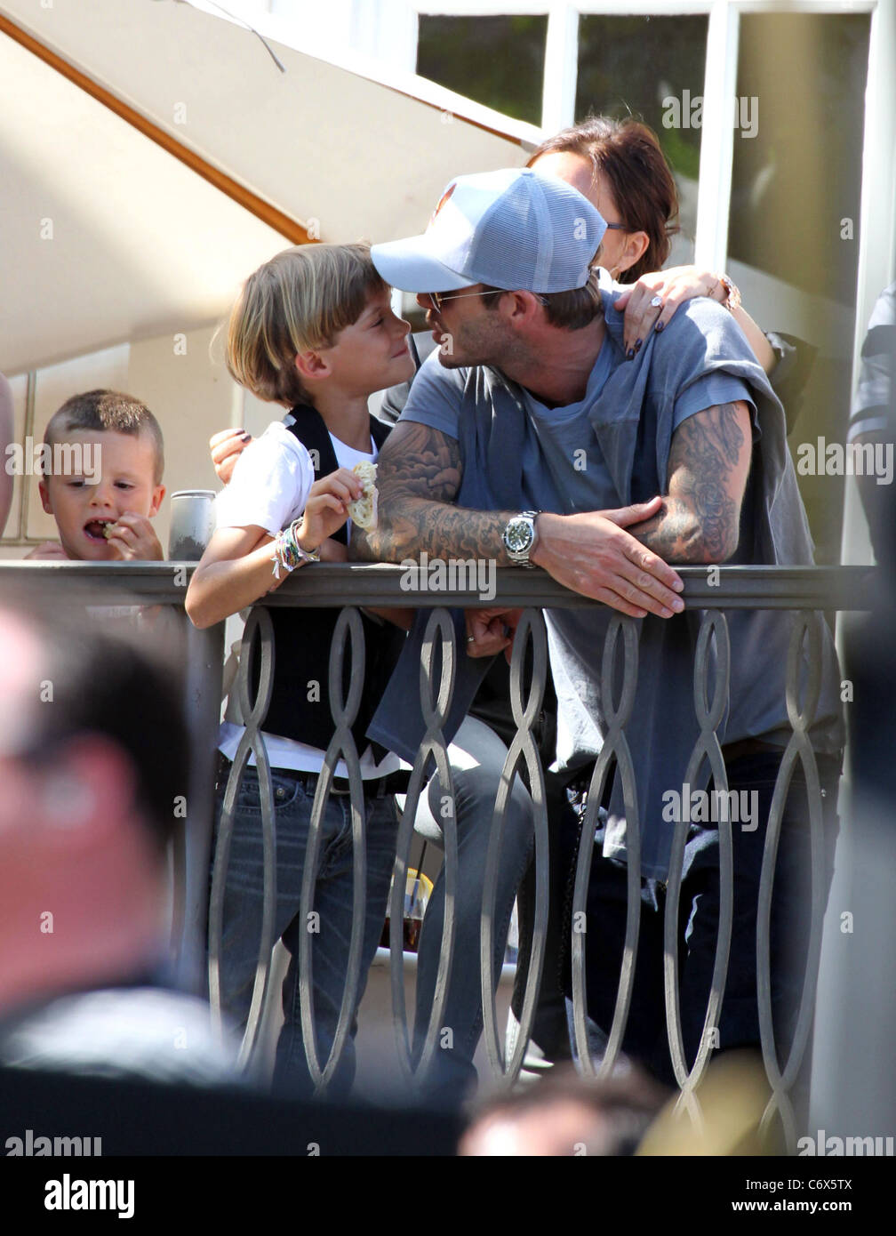 David Beckham küsst seinen Sohn Romeo Beckham, während gerade die Jonas Brothers in The Grove von einem Balkon Los Angeles durchführen, Stockfoto