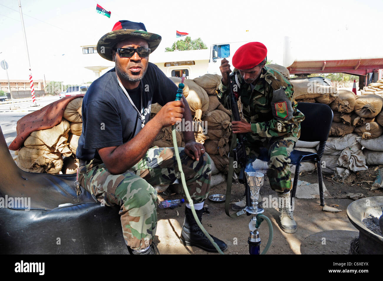 Zwei Truppen von der NTC Rauchen eine Pip auf einem Kontrollpunkt auf dem nach außen Rock von Benghazi Stockfoto