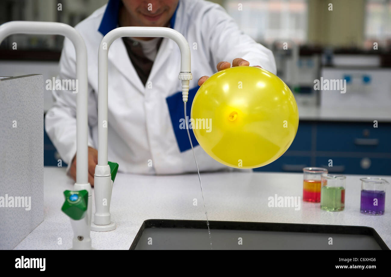 Ein Lehrer für Naturwissenschaften beugt Wasser aus einem Hahn mit statischen aus einem Ballon. Stockfoto