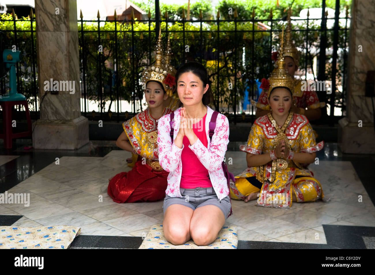 Eine Thai-Frau in einem lokalen Tempel zu beten. Sie wird von traditionellen thailändischen Tänzern begleitet. Stockfoto