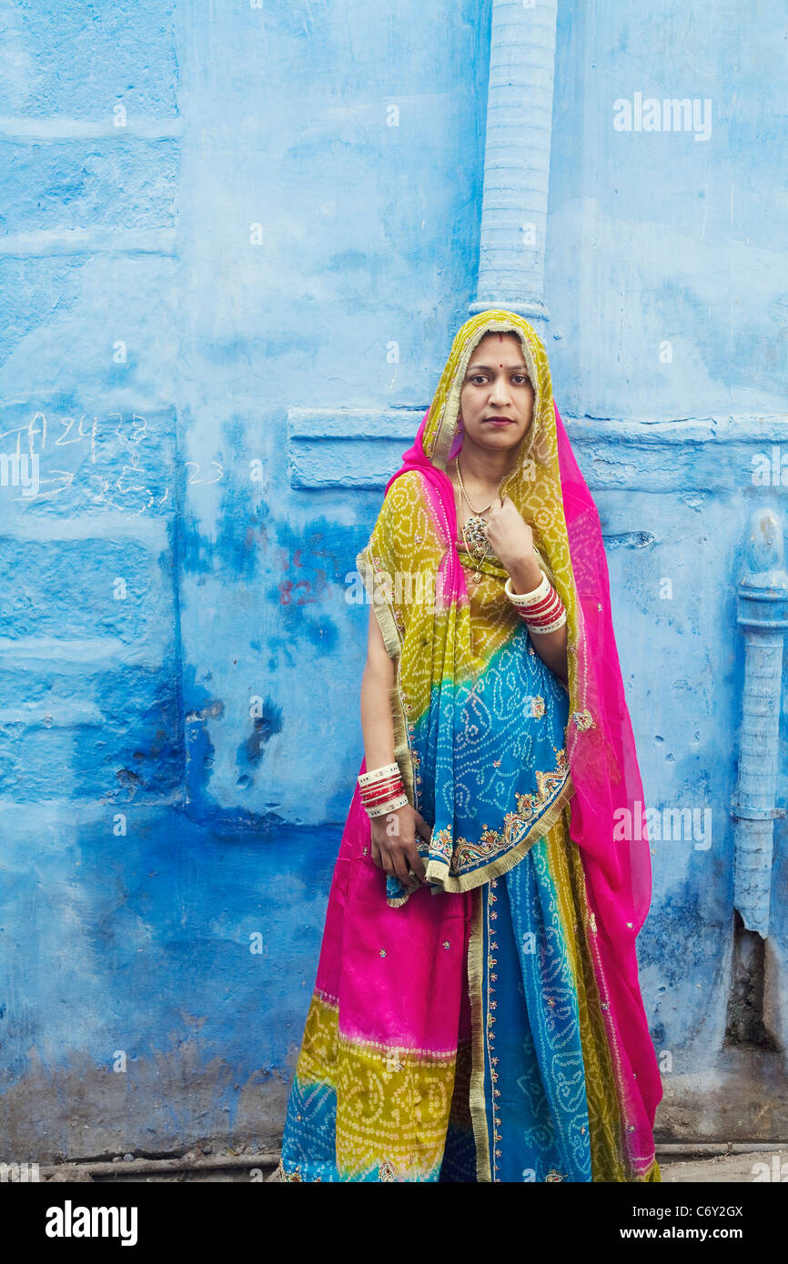 Eine Frau in traditioneller Kleidung steht vor einer Wand in die berühmte "Blaue Stadt" von Jodhpur, Indien im Staat Rajasthan Stockfoto