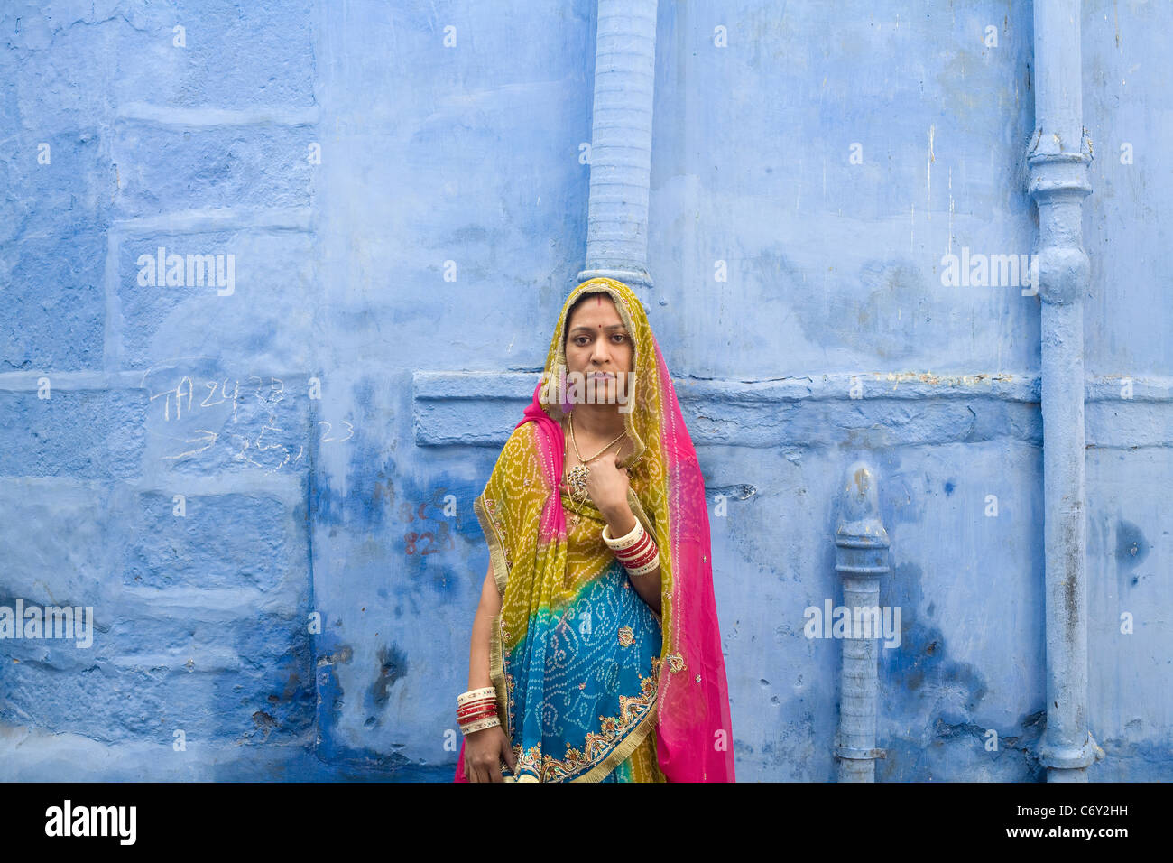 Eine Frau in traditioneller Kleidung steht vor einer blauen Wand in die berühmte "Blaue Stadt" von Jodhpur, Indien im Staat Rajasthan Stockfoto
