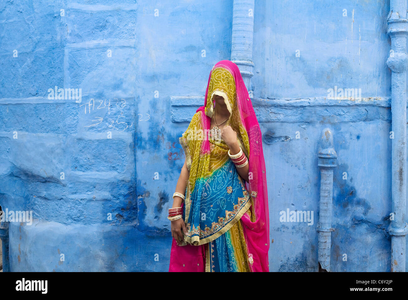 Eine Frau in traditioneller Kleidung steht vor einer der berühmten blauen Häuser von Jodhpur, Indien Rajasthan Zustand Stockfoto