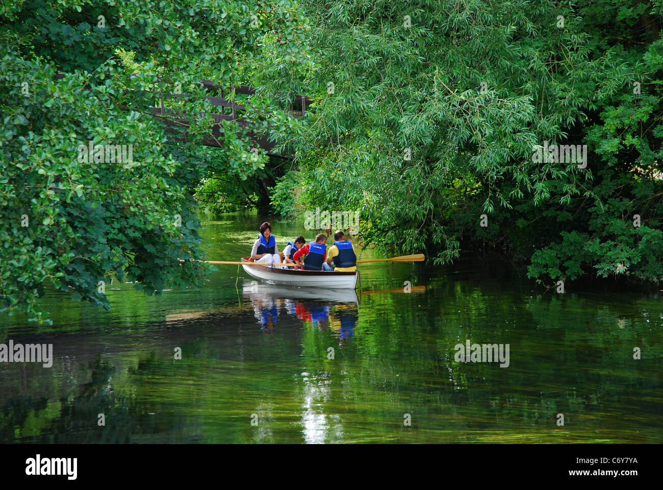 Familie im Ruderboot vorbei durch Bäume auf friedliche Stream in Cookham Stockfoto