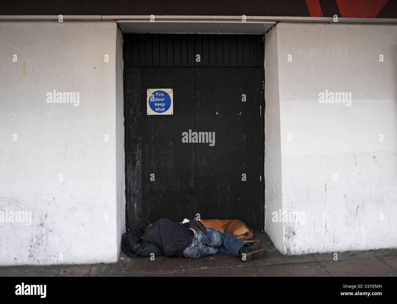 Sleeping Rough oder rauen Schwellen Stadtzentrum Brighton - Mann und sein Hund sackte schlafend in einem Hauseingang in West Street Stockfoto