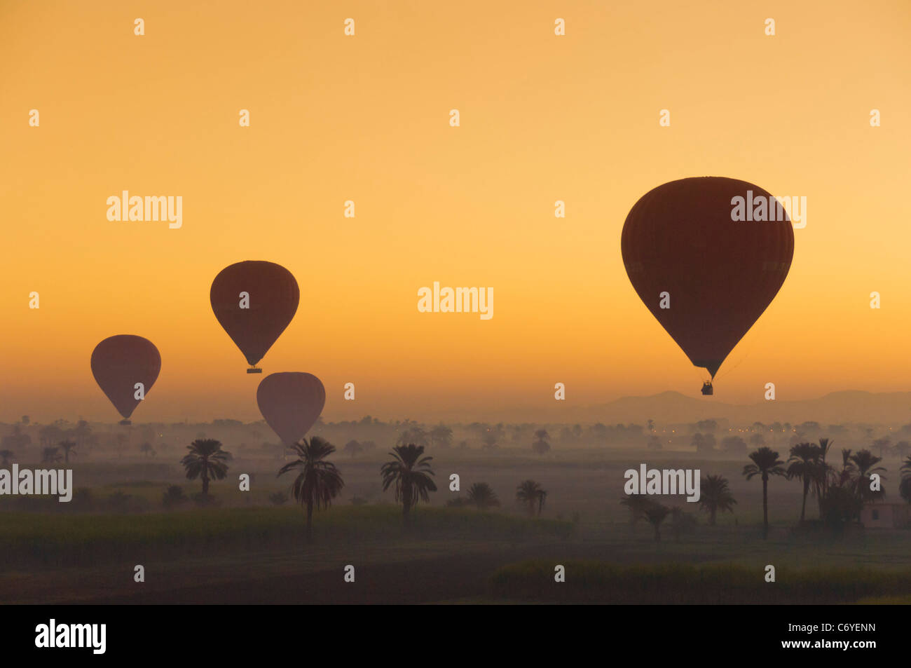 Heißluft-Ballone bei Sonnenaufgang über der Wüste in der Nähe von Luxor Ägypten Stockfoto