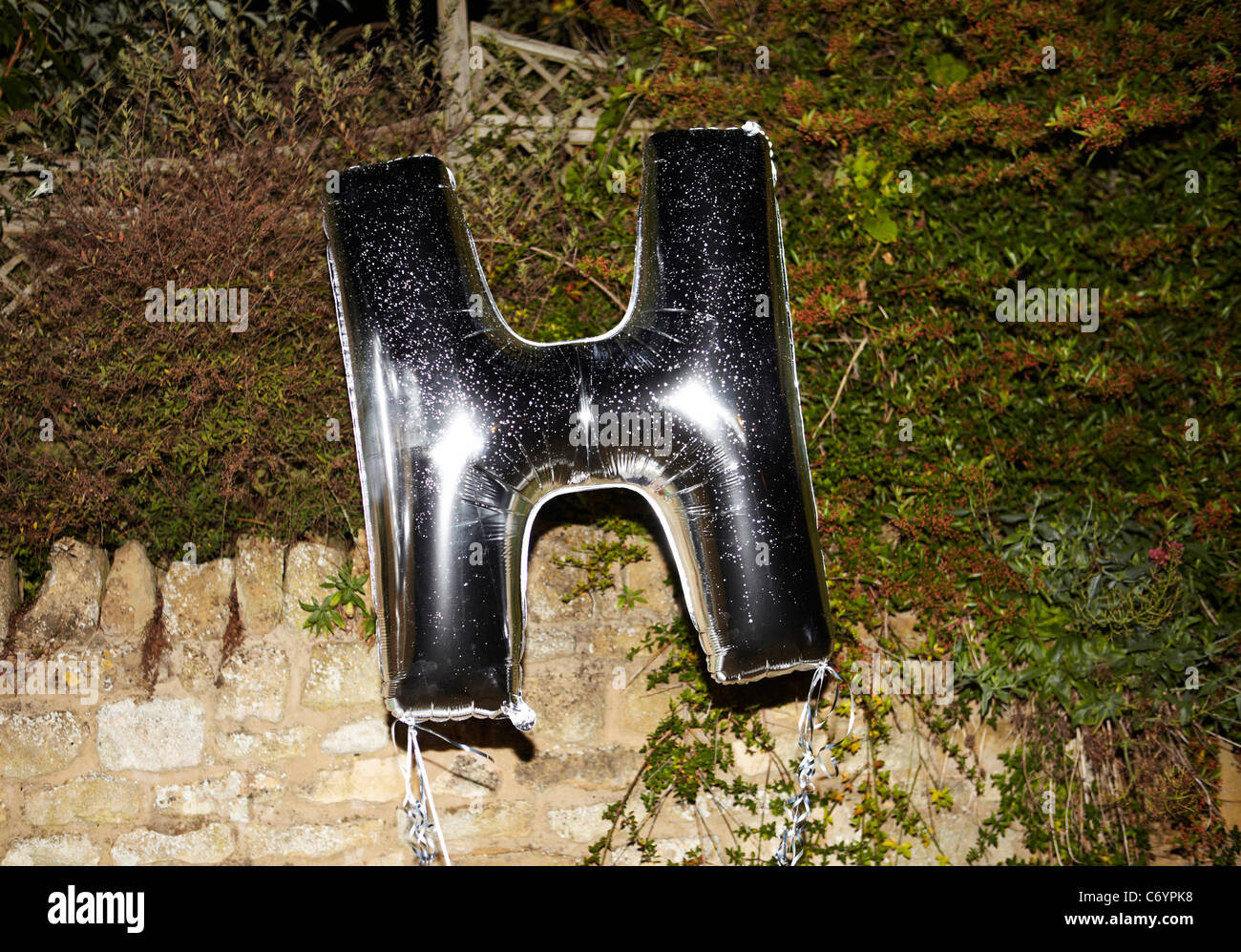 'H' Silber Helium-Ballon in einem Garten. Stockfoto