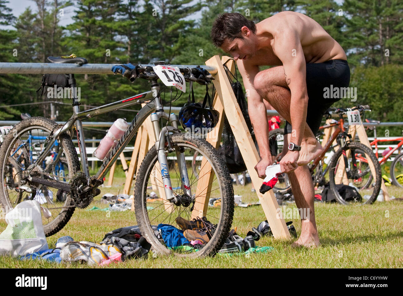 Männliche Triathlon Racer Änderungen Ausrüstung während der Off-Road-Triathlon-Renn-Event vor der Mountainbike-Touren Stockfoto