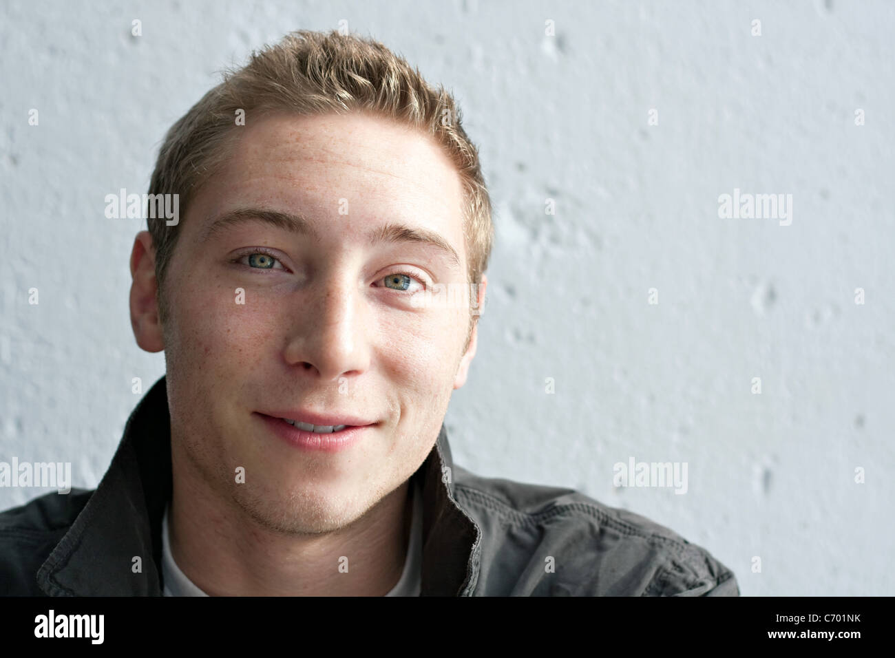 Porträt eines schönen lächelnden jungen Mannes in seinen frühen Zwanzigern mit schmutzigen blonden Haaren hautnah. Stockfoto