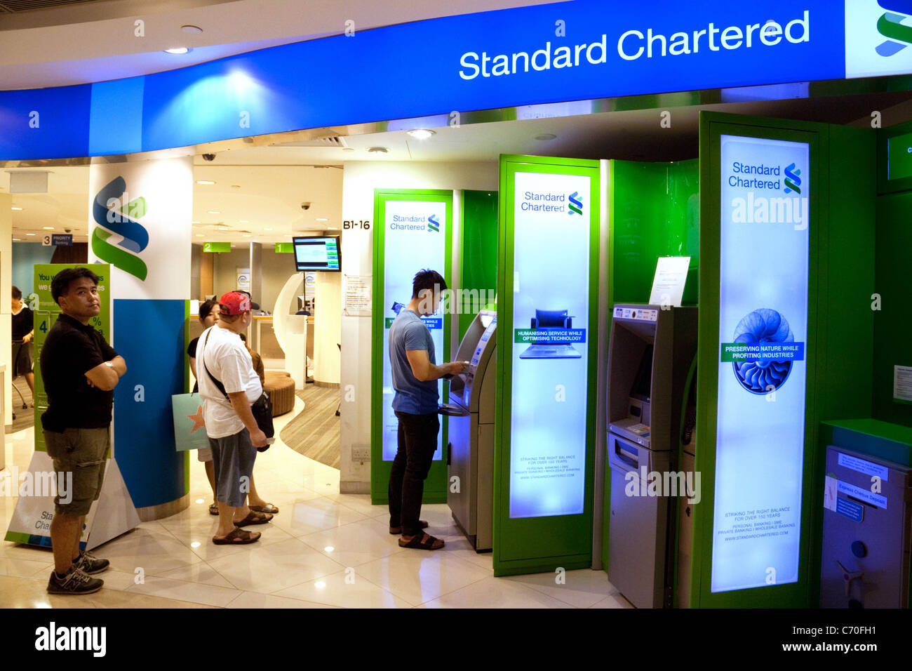 Leute, die Geld von einem Standard Chartered Bank ATM in Singapur Asien Stockfoto