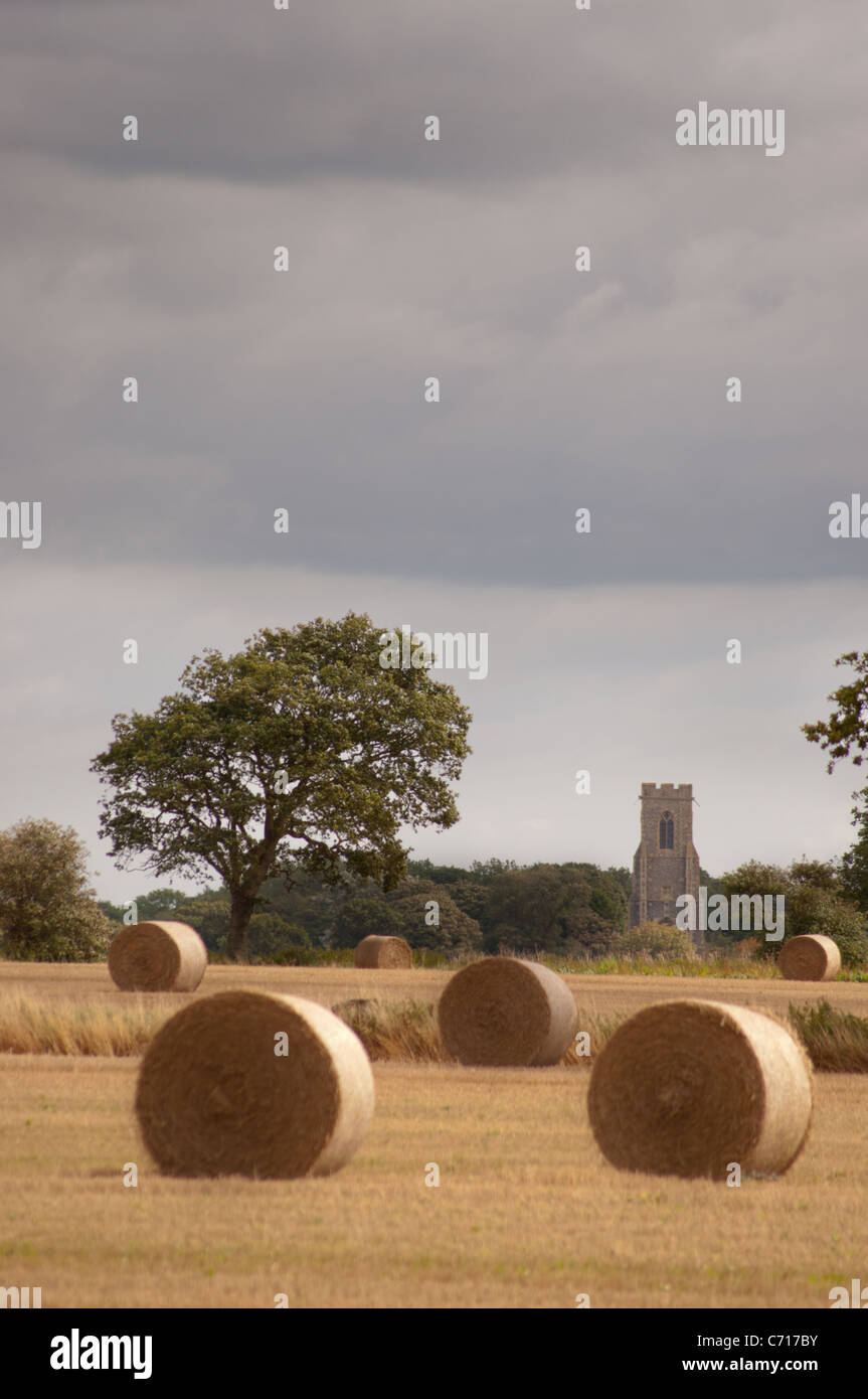 Runde Stroh Kautionen in Norfolk Feld mit Kirche Stockfoto