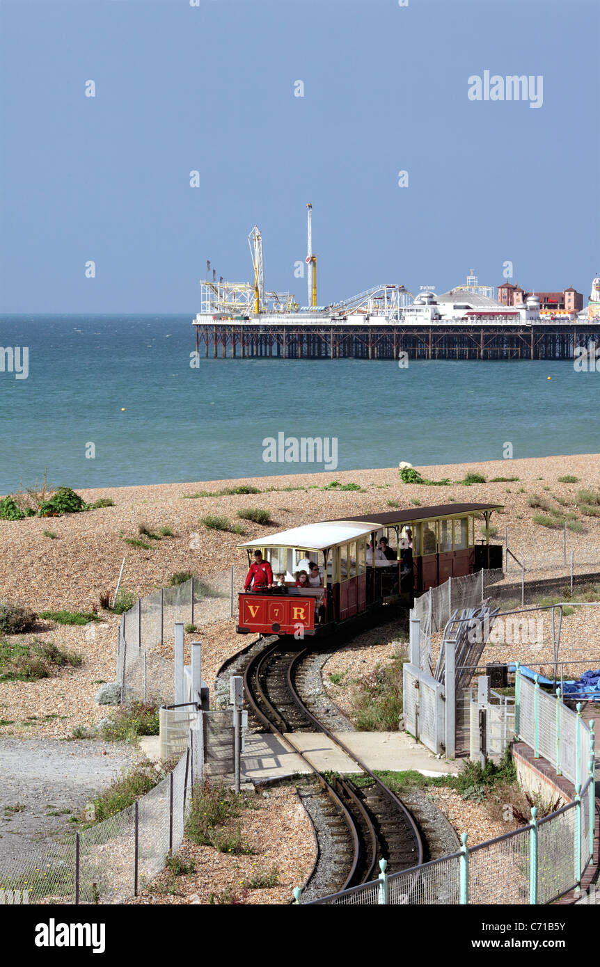 Ein Zug auf der Volks-Bahn schlängelt sich um eine doppelte Biegung mit Brighton Pier im Hintergrund. Stockfoto