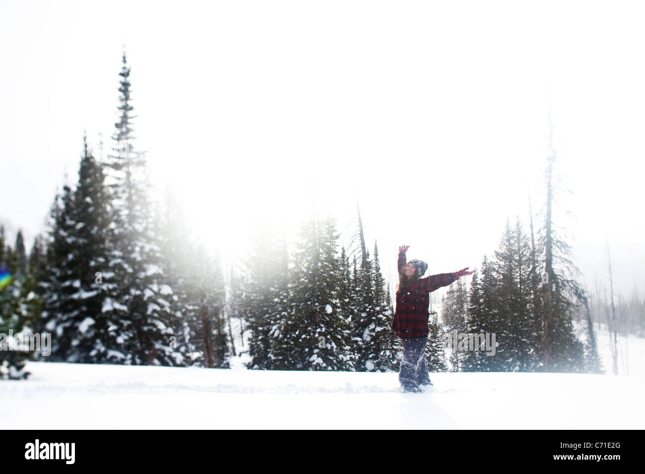 Eine schöne Frauen Lächeln beim Wandern durch unberührte Schneefeld bei Sonnenuntergang in Wyoming. Stockfoto