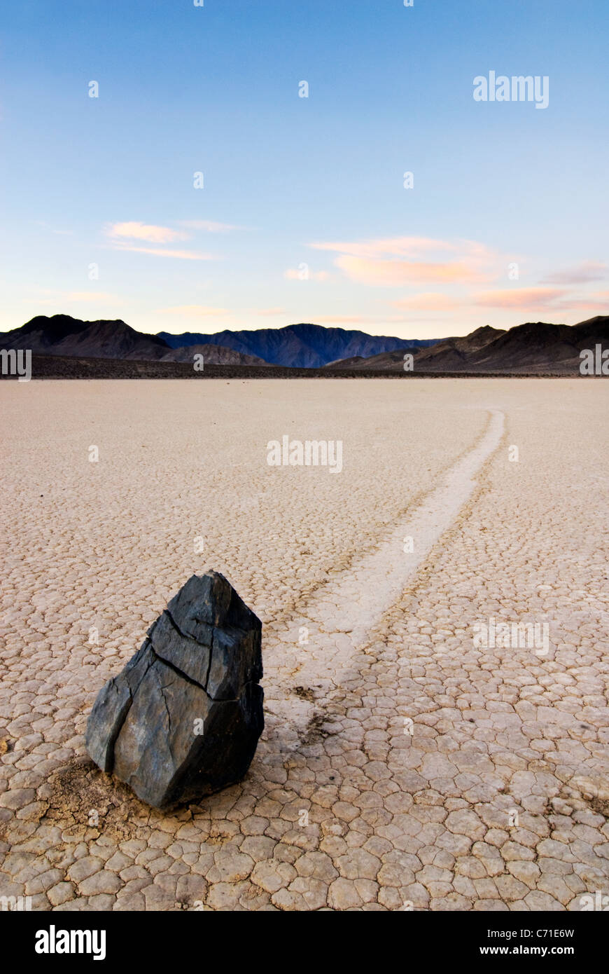 Ein Fels hinterlässt eine Spur von seiner Bewegung über die Rennstrecke im Death Valley National Park bei Sonnenuntergang, CA. Stockfoto
