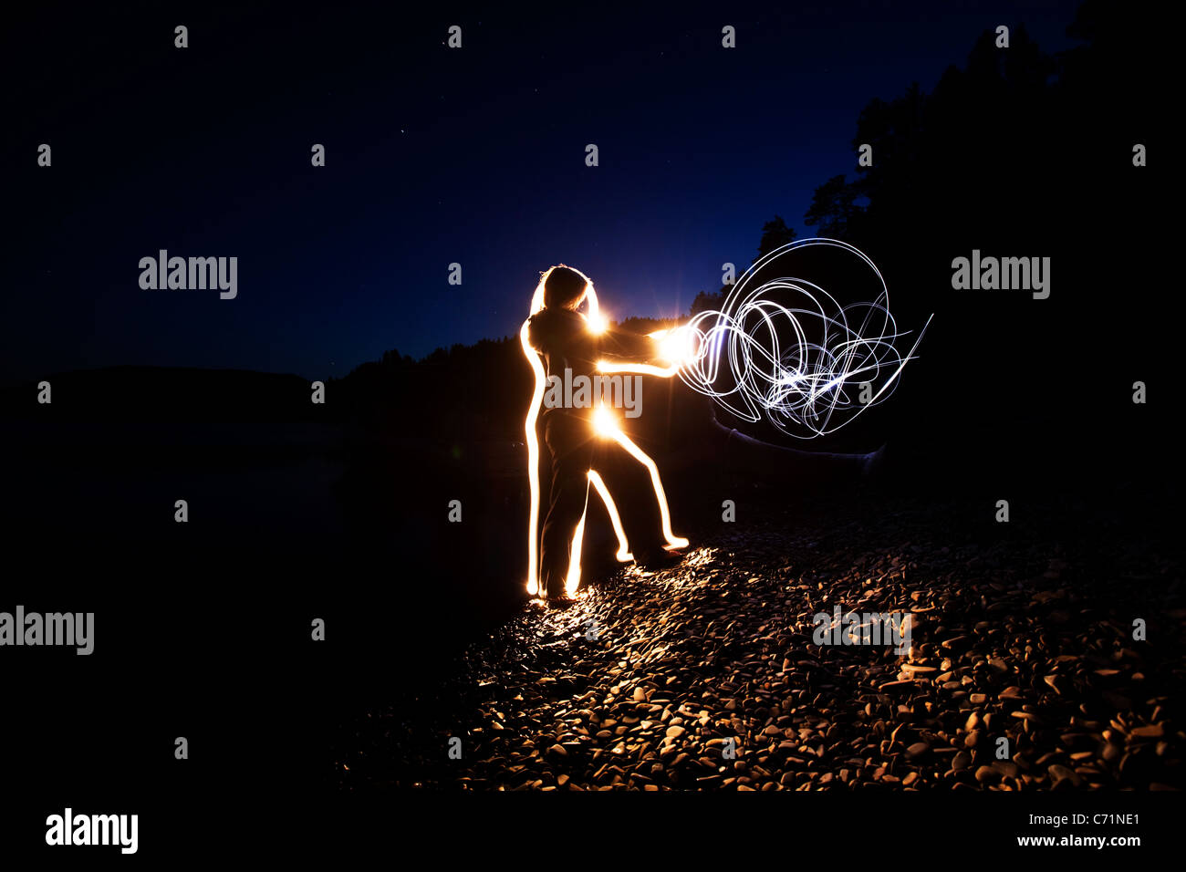 Eine Frau schickt Energie durch ihren Körper und ihre Hände bei Sonnenuntergang in Idaho. Dieses Lightpainting-Bild wurde mit einer langen ex erstellt. Stockfoto
