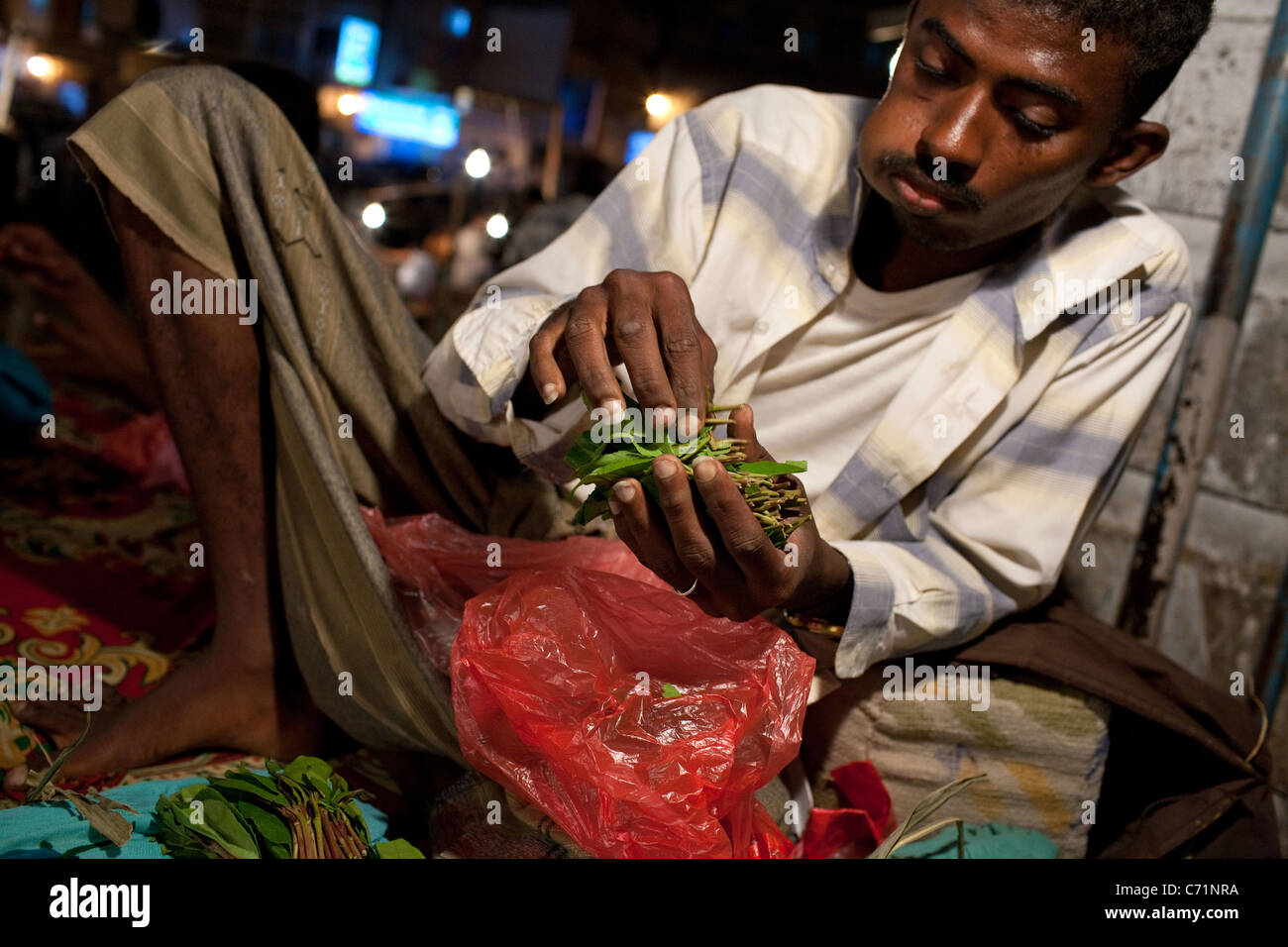 Ein Mann kaut und vertreibt Khat (Qat) in der Nacht Khat Markt in Aden, Jemen. Stockfoto