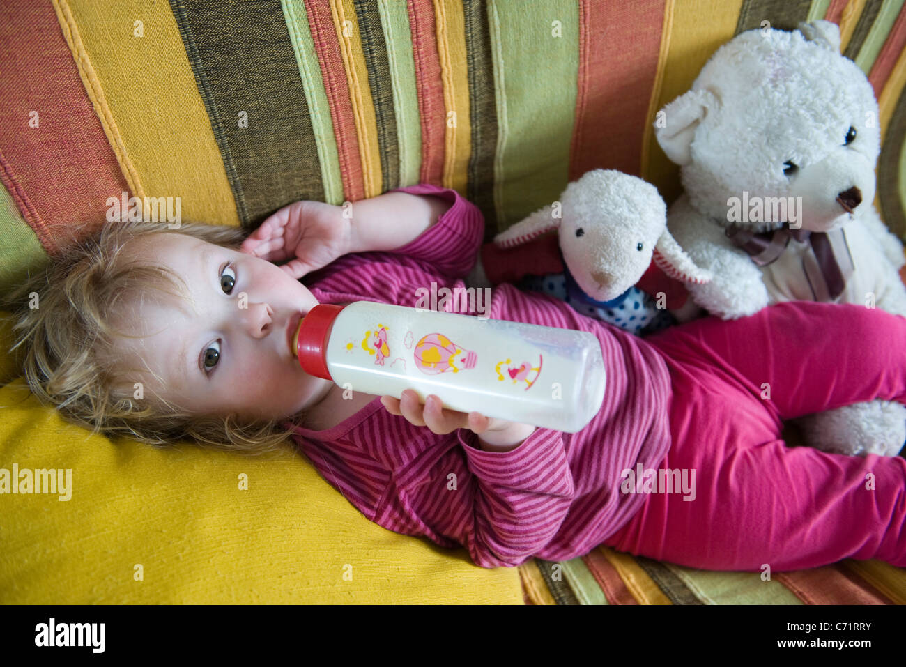 Babymädchen hinlegen, Konsummilch aus Babyflasche Stockfoto