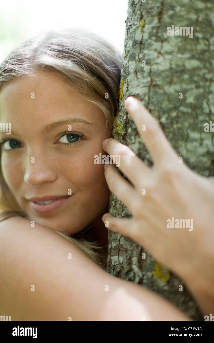 Junge Frau umarmt Baum, Porträt Stockfoto