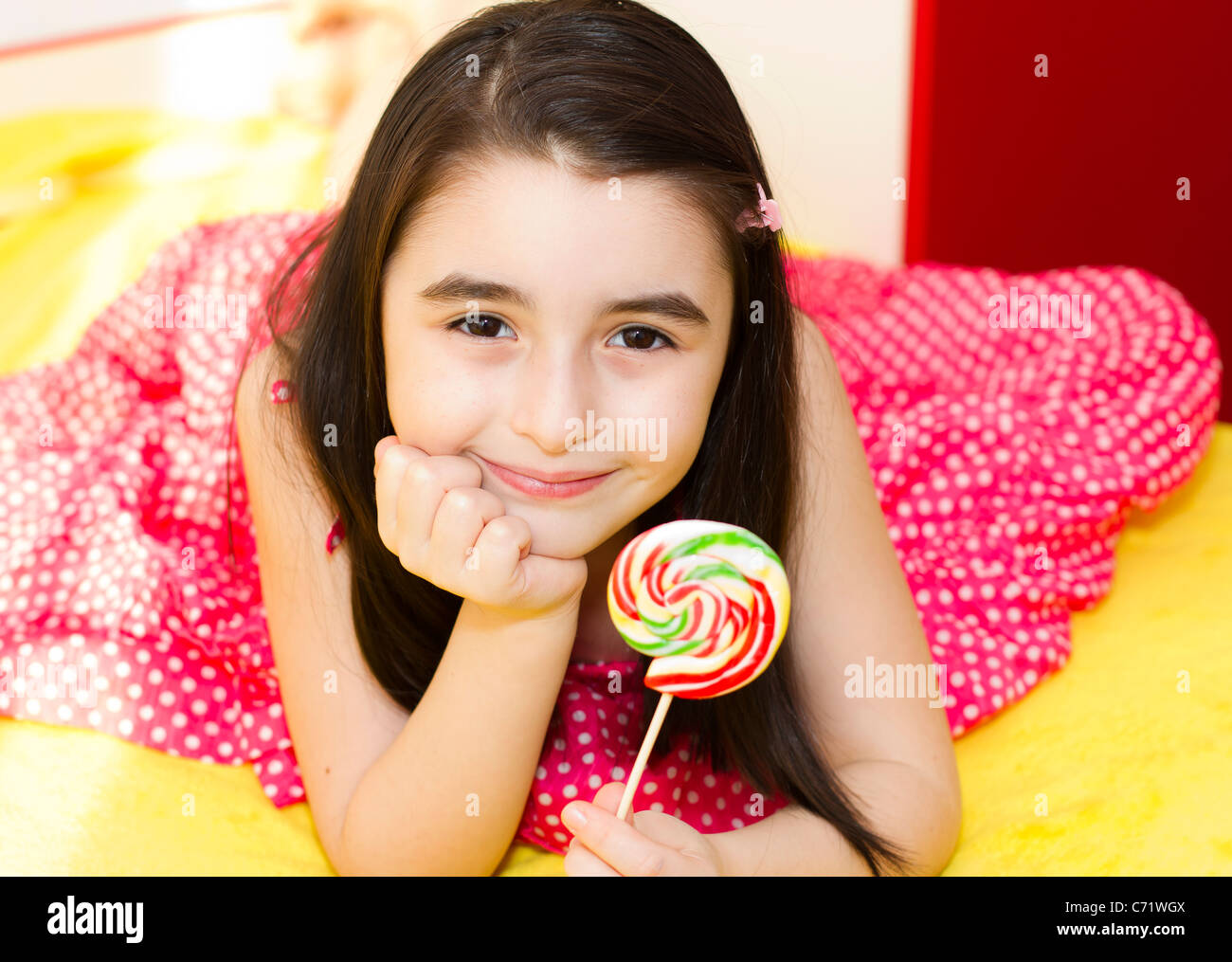 Kleines Mädchen mit Lollipop in ihrem Schlafzimmer. Stockfoto
