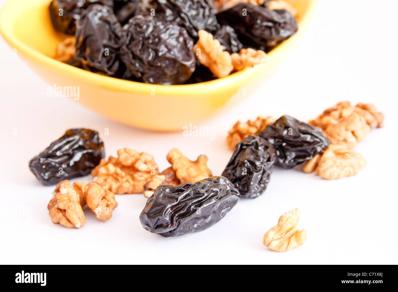 Pflaumen mit Nüssen in Schüssel auf weißem Hintergrund Stockfoto