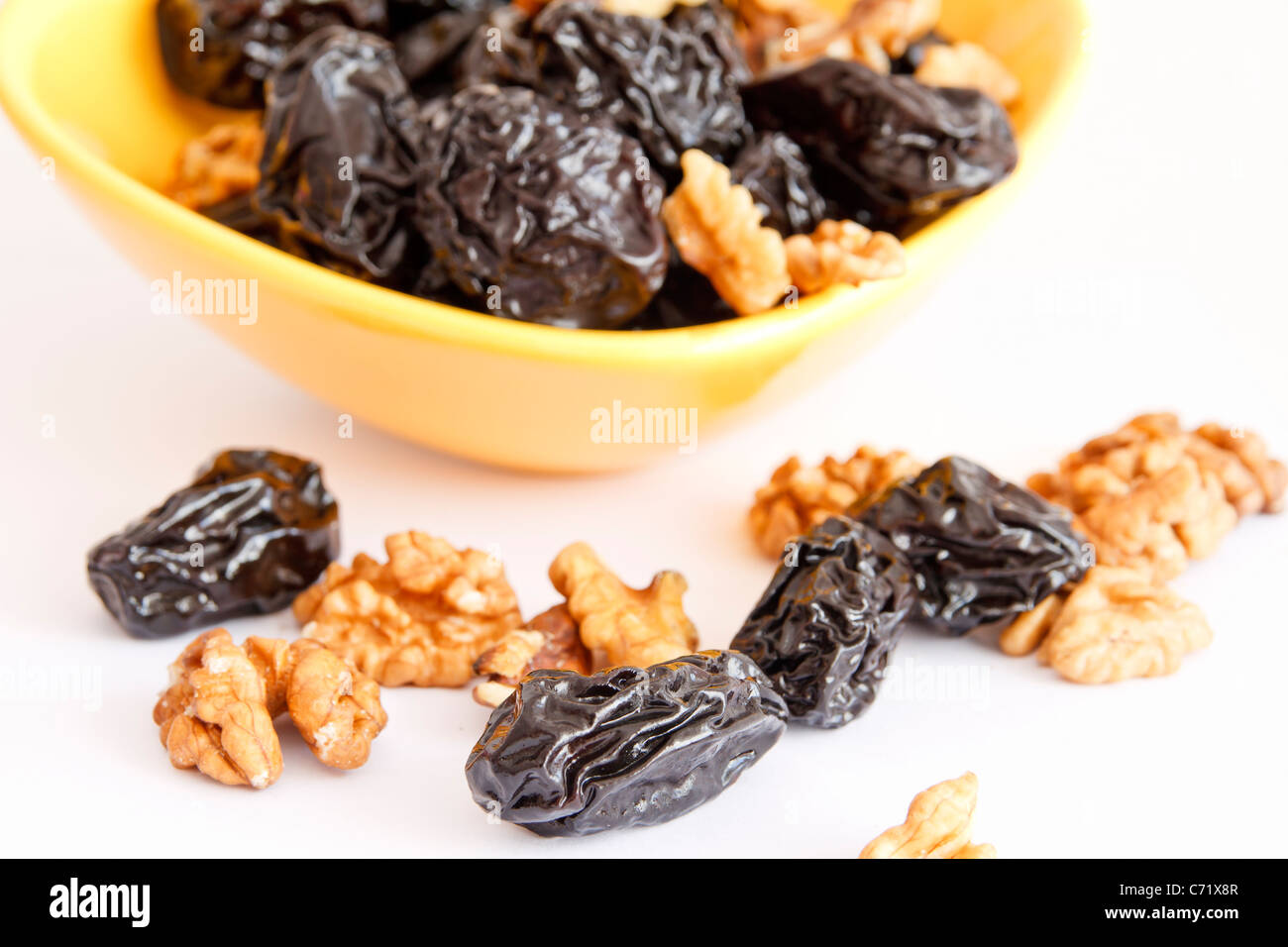 Pflaumen mit Nüssen in Schüssel auf weißem Hintergrund Stockfoto