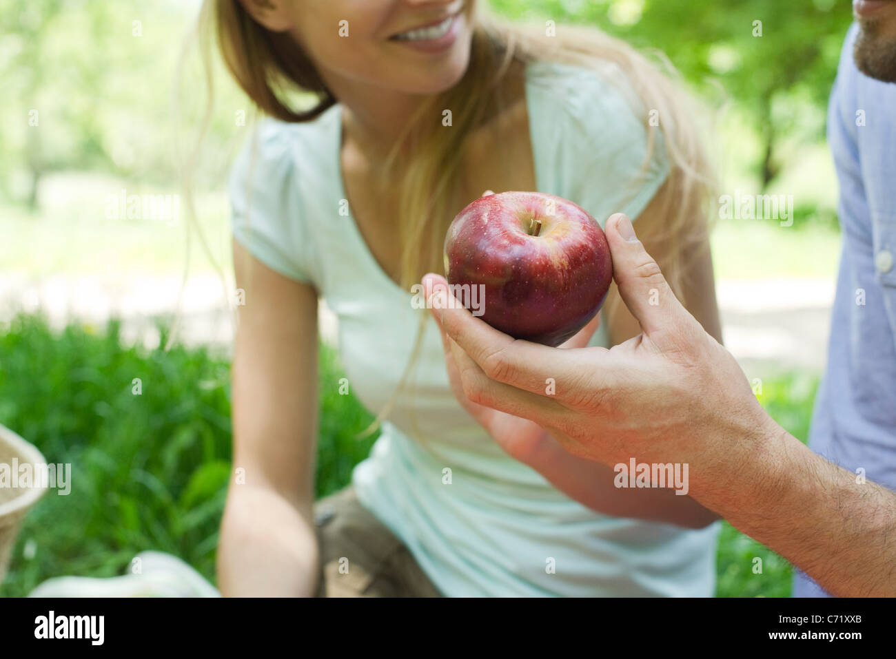 Mann, hält Apple bei Picknick, beschnitten Stockfoto