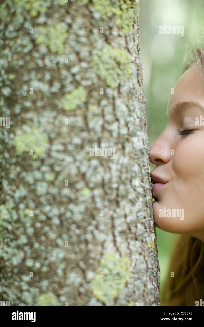 Junge Frau küssen Baum Stockfoto