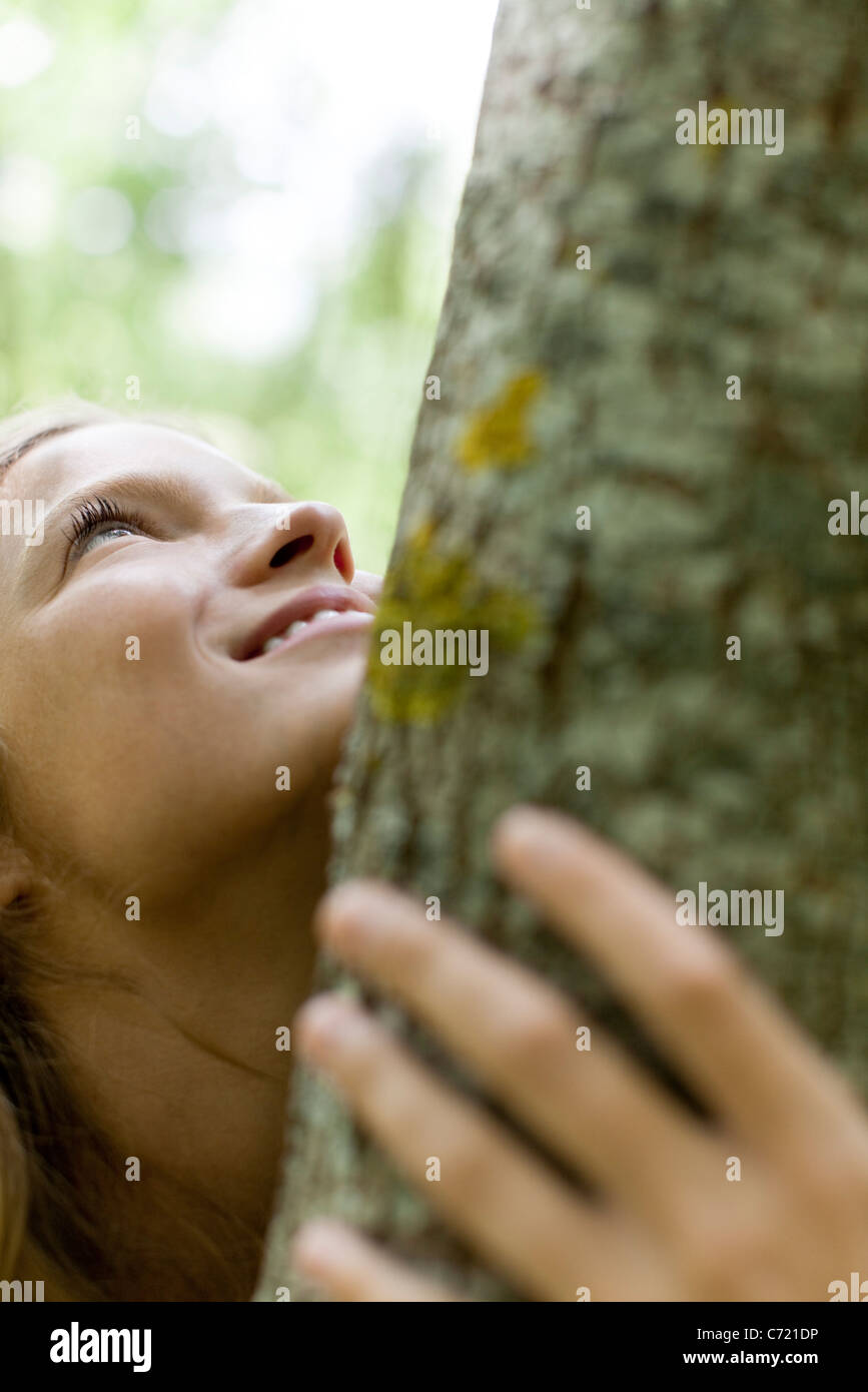 Junge Frau umarmt Baum beschnitten Stockfoto