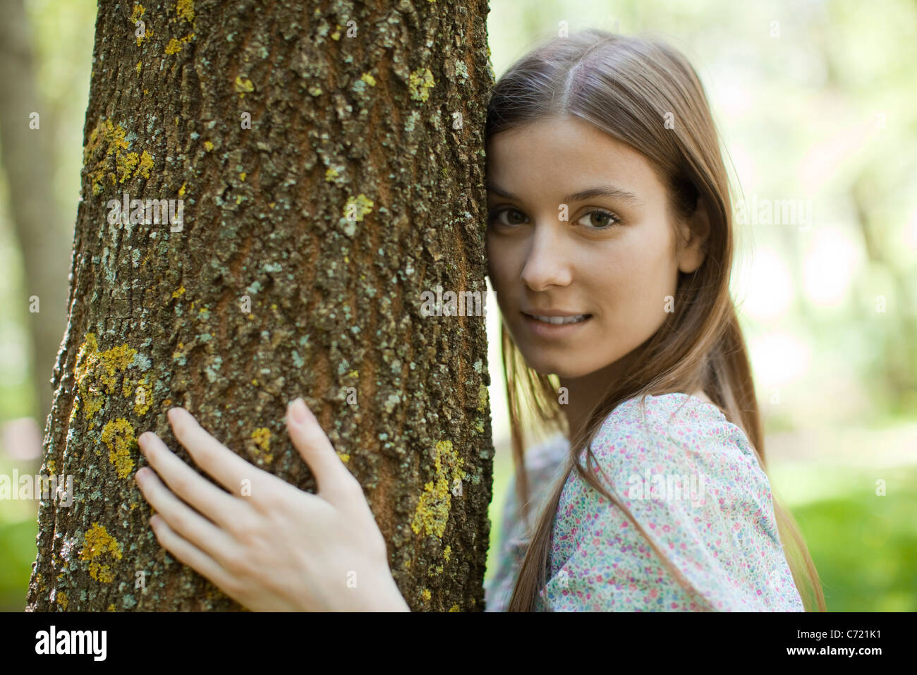 Junge Frau umarmt Baum, Porträt Stockfoto