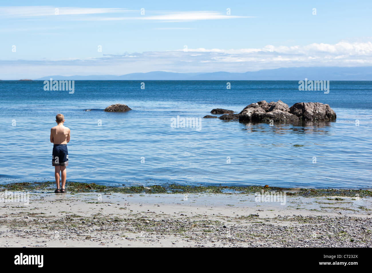Ein Junge wird ungern ins Wasser an einem Strand East Sooke Park, BC, Kanada. Stockfoto