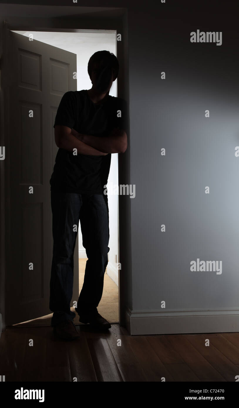 Männlichen Arme verschränkt durch eine teilweise offene Tür an die Wand gelehnt. Stockfoto