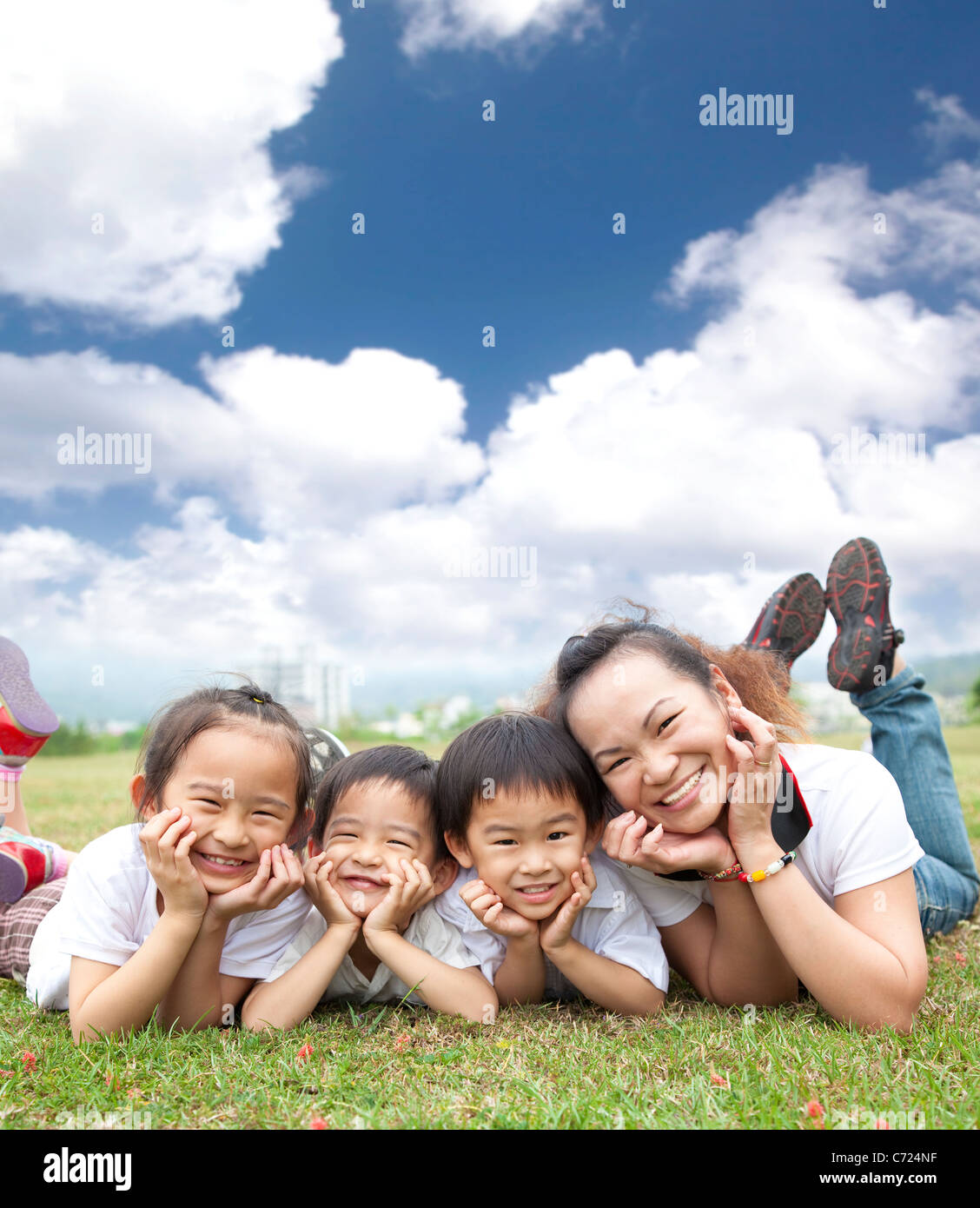 asiatische Familienglück auf dem Rasen mit Cloud-Hintergrund Stockfoto