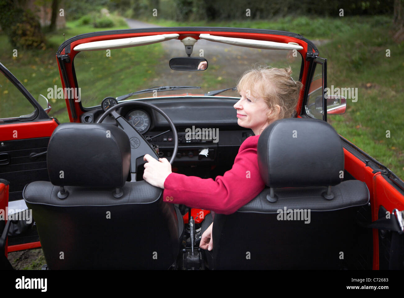 Dame auf dem Beifahrersitz eines roten klassischen linken Hand warten fahren VW Käfer Auto, England, UK Stockfoto