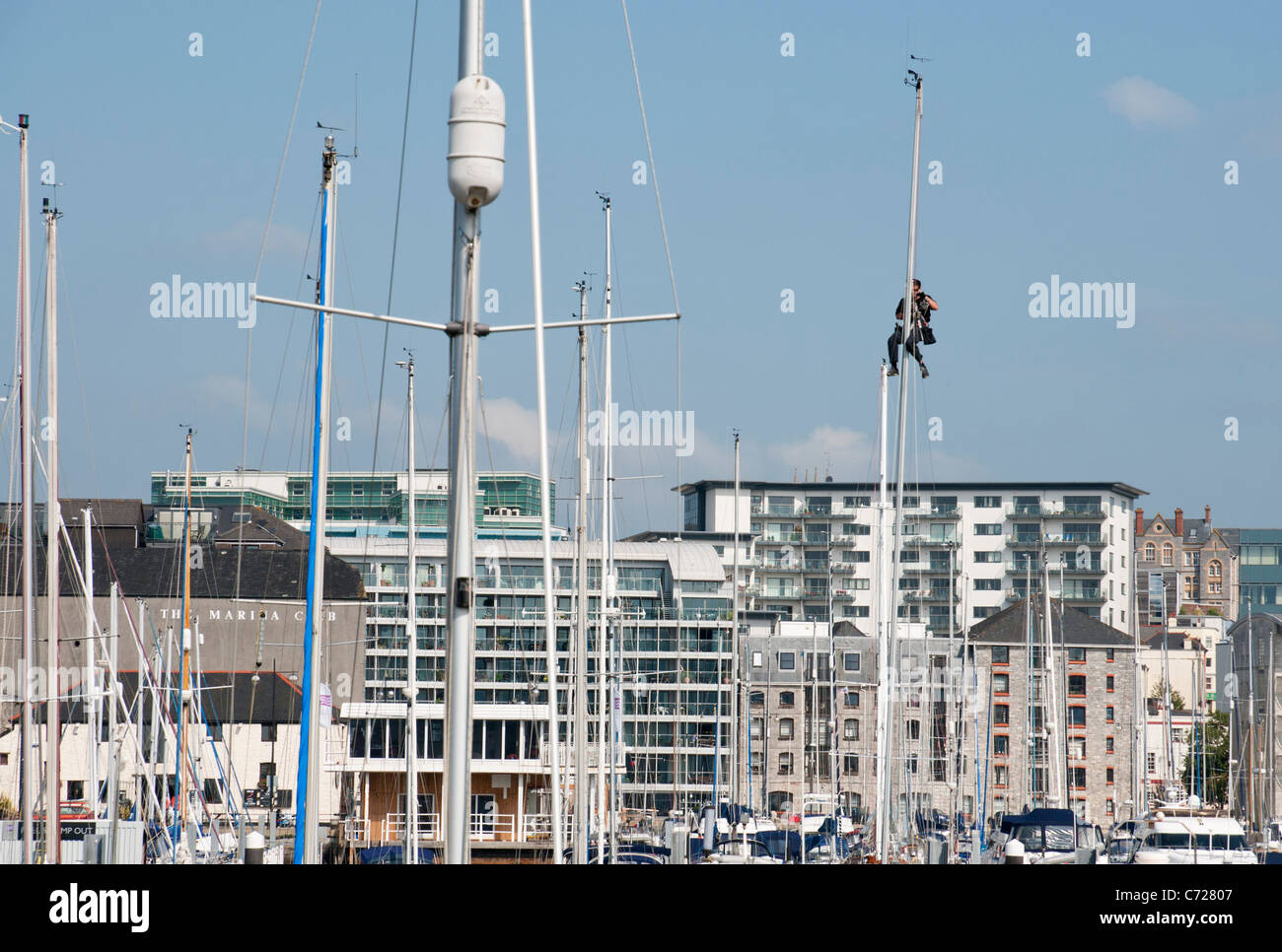 Mann arbeitet auf einem Mast ein Sportboot ankern in Sutton Harbour, Plymouth, Devon Stockfoto