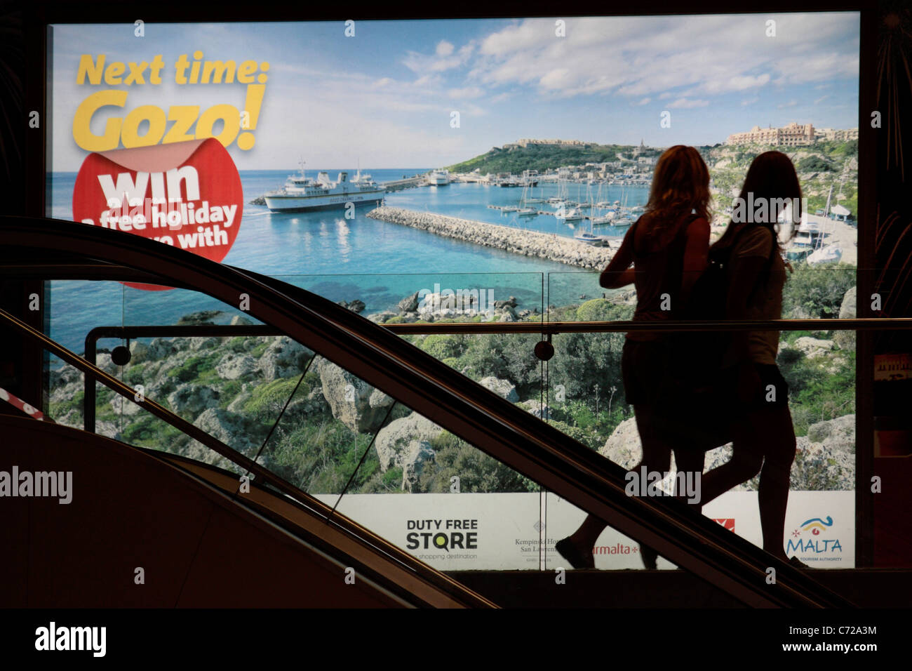 Abfliegende Passagiere auf dem Internationalen Flughafen in Malta durch ein Plakat, die Förderung des Tourismus in der benachbarten Insel Gozo Stockfoto
