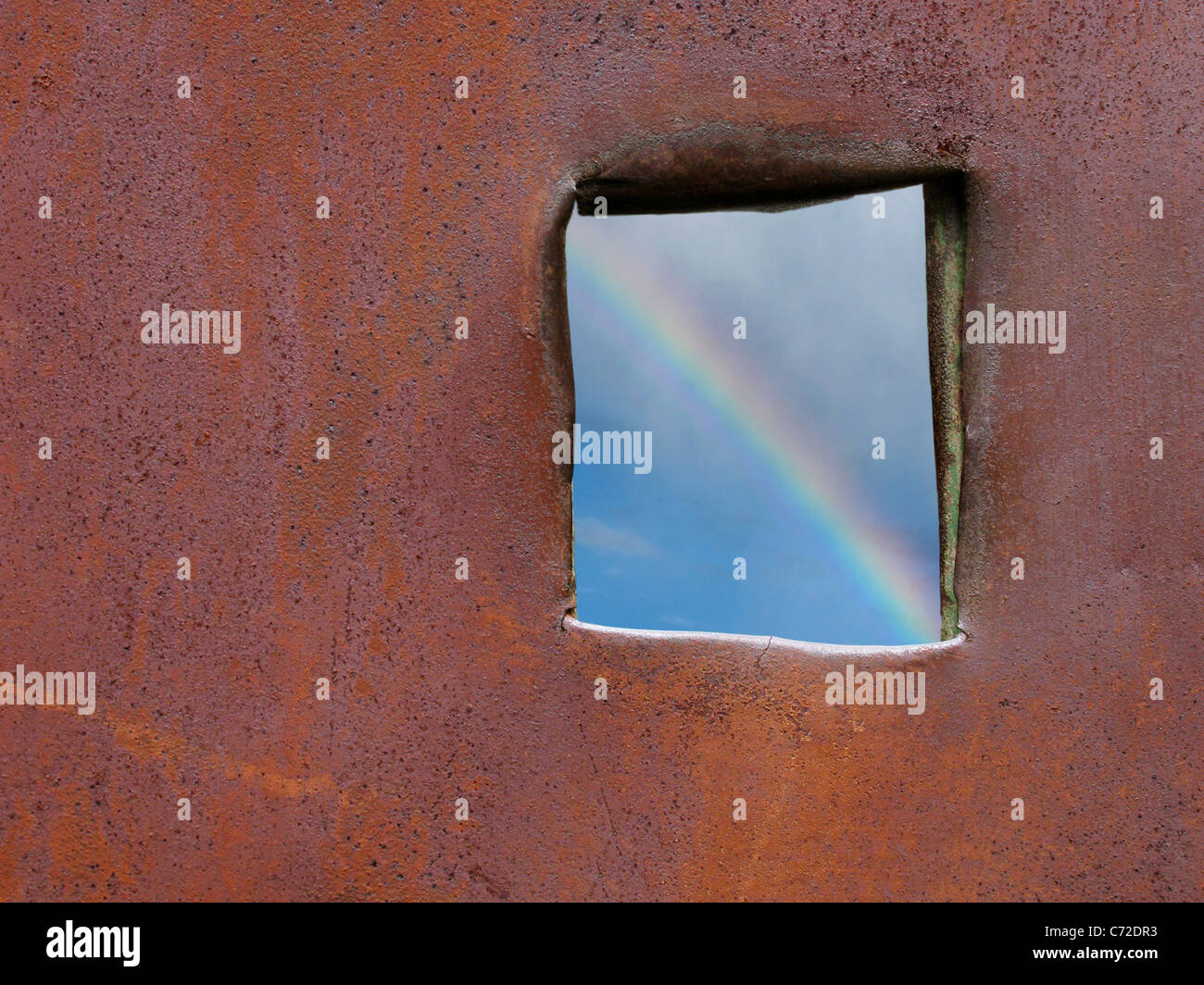 hoffe: Blick auf Regenbogen durch Loch in eine rostige Oberfläche Stockfoto